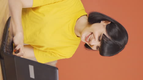 Vertical-video-of-Young-woman-working-on-laptop-with-happy-expression.